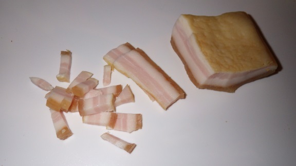 A picture of a piece of boiled bacon being sliced.