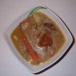 A picture of a bowl of lentil soup with smoked pork.