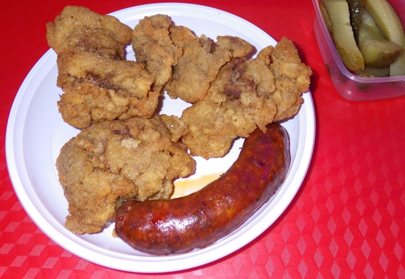A picture of some deep-fried chicken liver pieces and a fried sausage on a plate.